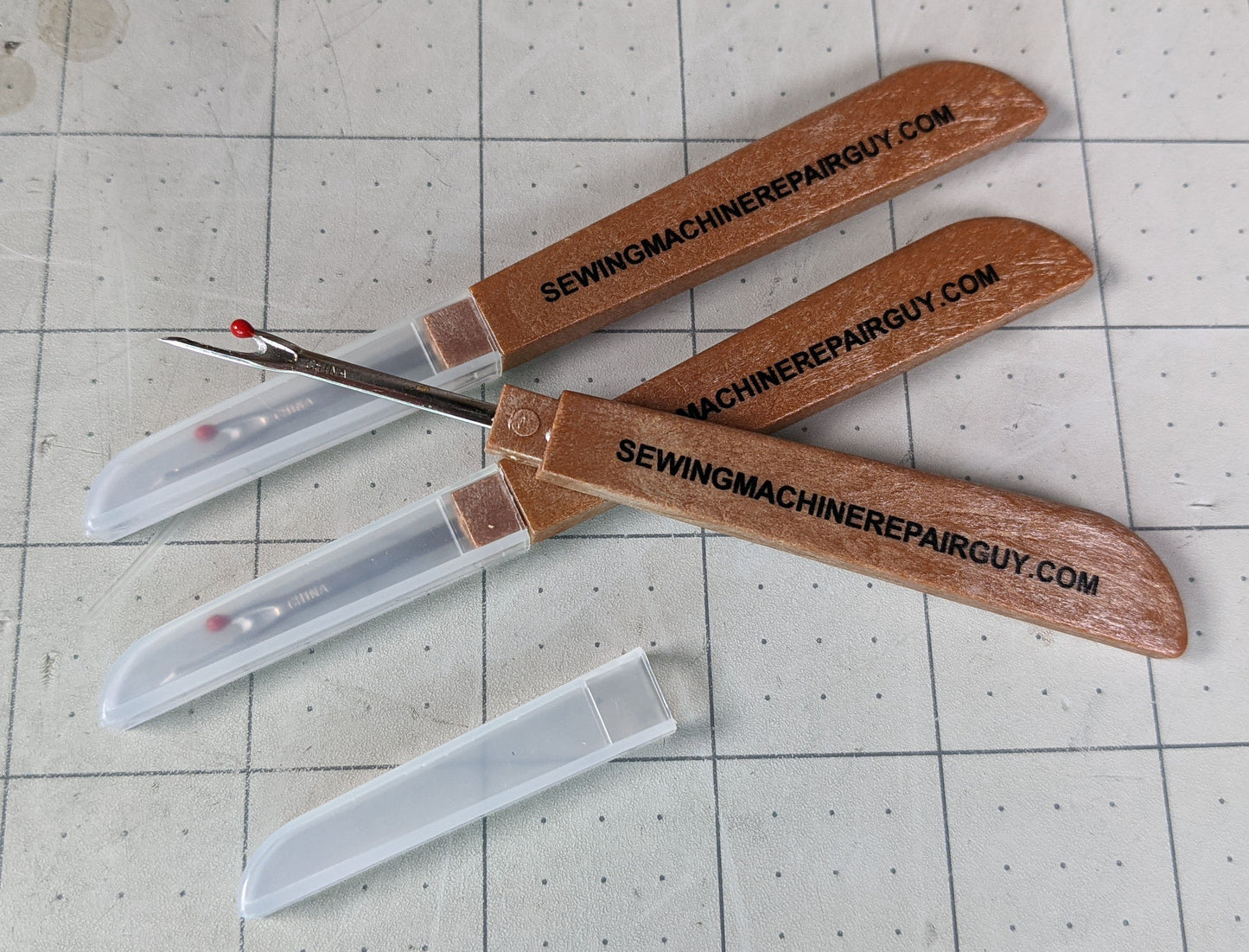 Three seam rippers and one logo sticker for Sewing Machine Repair Guy